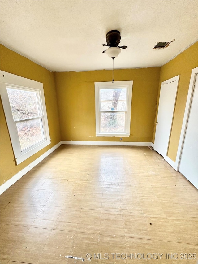 unfurnished dining area with ceiling fan, a textured ceiling, and a wealth of natural light