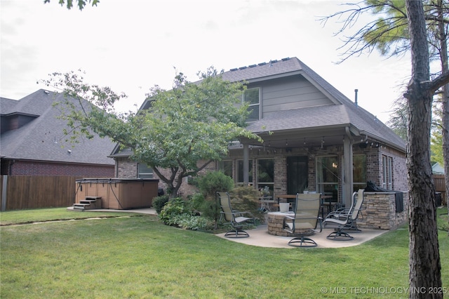 rear view of house with a hot tub, a patio, and a yard