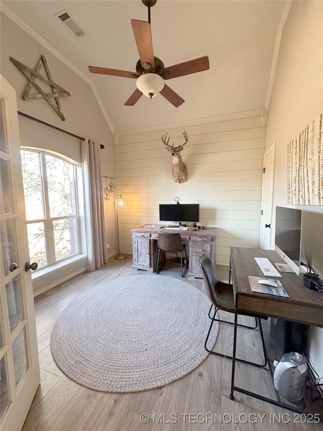 home office with lofted ceiling, ornamental molding, wooden walls, ceiling fan, and light hardwood / wood-style floors