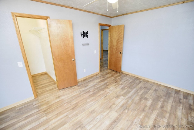 unfurnished bedroom featuring crown molding, a textured ceiling, and light wood-type flooring