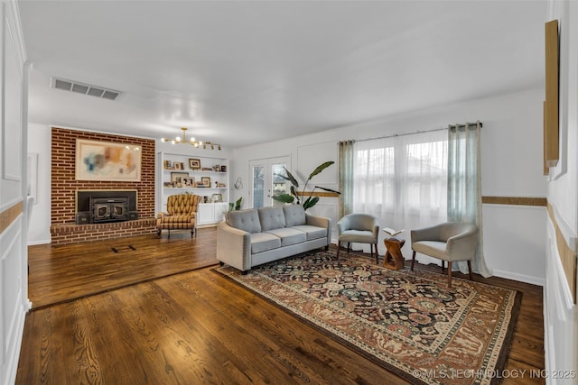 living room featuring hardwood / wood-style floors, built in shelves, a fireplace, and a chandelier