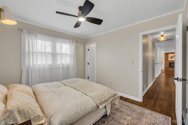 bedroom with dark hardwood / wood-style flooring, a brick fireplace, crown molding, and ceiling fan