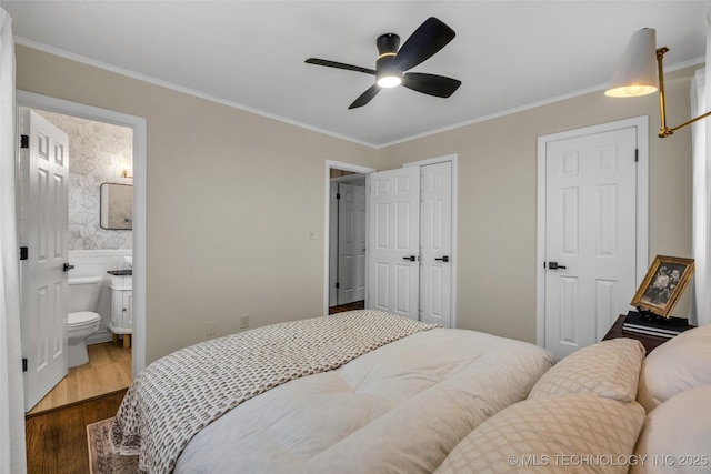 bedroom with ensuite bathroom, ornamental molding, ceiling fan, dark wood-type flooring, and a closet