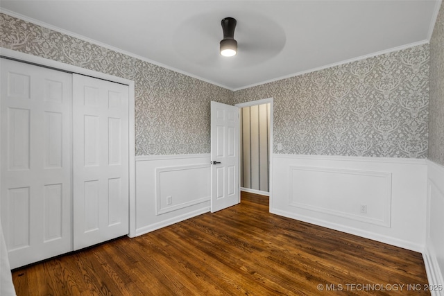 unfurnished bedroom featuring crown molding, dark hardwood / wood-style floors, ceiling fan, and a closet