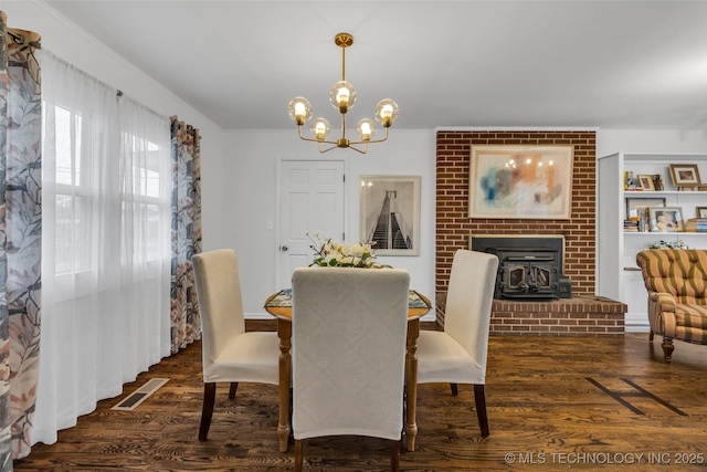 dining area featuring built in shelves, dark hardwood / wood-style floors, a chandelier, and crown molding