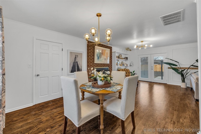 dining area featuring crown molding, dark hardwood / wood-style floors, a notable chandelier, a brick fireplace, and french doors