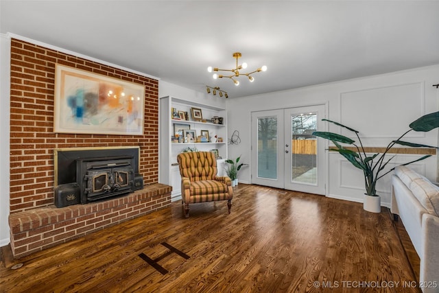 sitting room with hardwood / wood-style flooring, a wood stove, a notable chandelier, and french doors