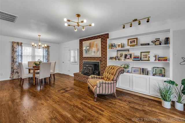 interior space featuring track lighting, dark hardwood / wood-style floors, built in features, and a notable chandelier