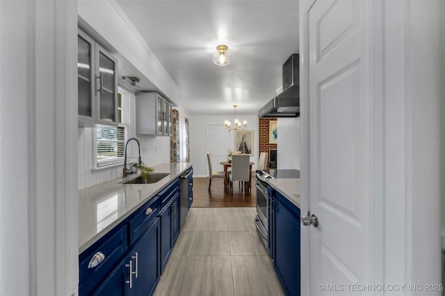 kitchen featuring blue cabinetry, sink, decorative light fixtures, stainless steel appliances, and wall chimney range hood