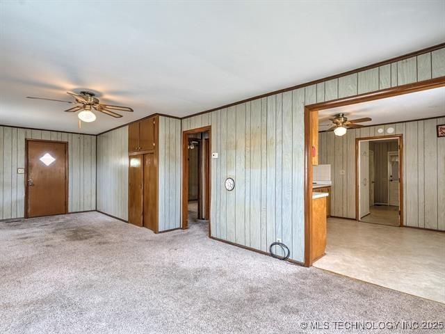 empty room with ceiling fan, ornamental molding, and light carpet