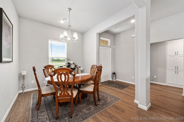 dining area with dark hardwood / wood-style flooring and an inviting chandelier