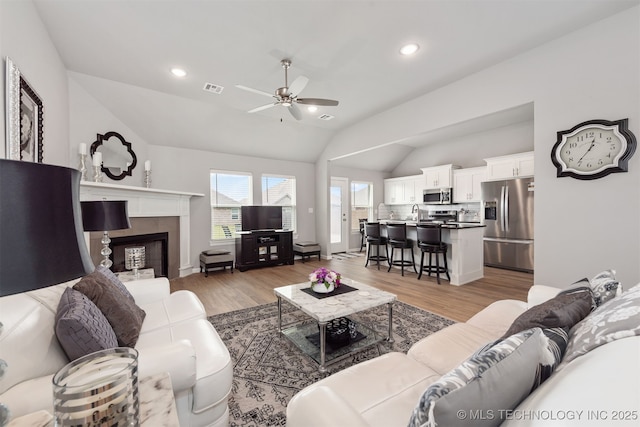 living room featuring vaulted ceiling, wood-type flooring, and ceiling fan