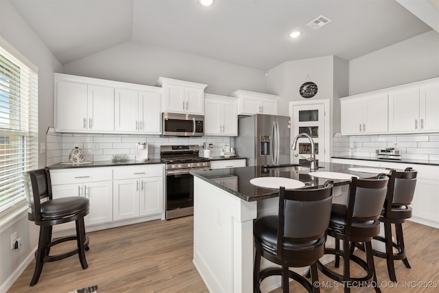 kitchen featuring sink, white cabinetry, a center island with sink, light wood-type flooring, and appliances with stainless steel finishes