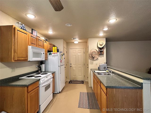 kitchen with sink, white appliances, kitchen peninsula, and a textured ceiling