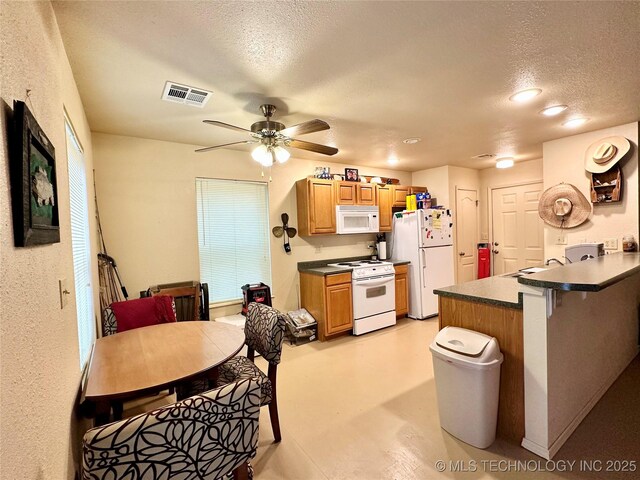 kitchen featuring a breakfast bar area, white appliances, ceiling fan, kitchen peninsula, and a textured ceiling