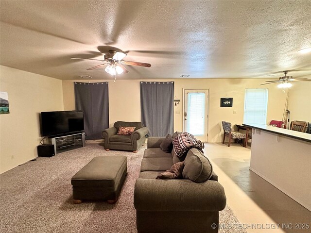 living room featuring ceiling fan, light colored carpet, and a textured ceiling