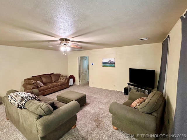 carpeted living room featuring ceiling fan and a textured ceiling