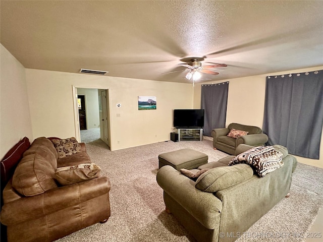 carpeted living room featuring ceiling fan and a textured ceiling