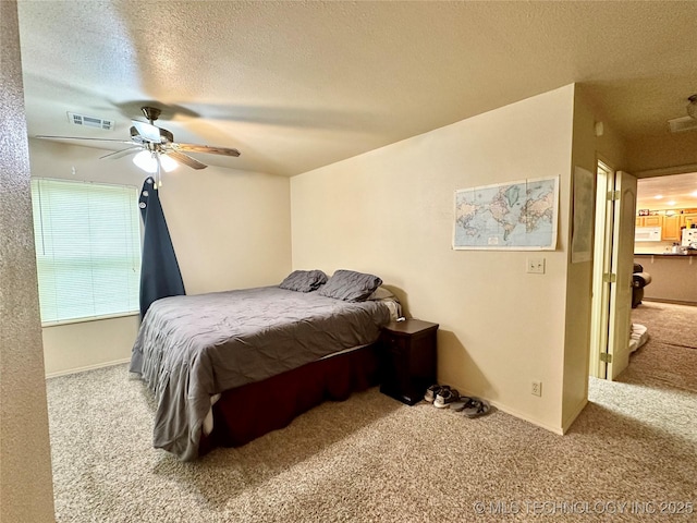 carpeted bedroom featuring ceiling fan and a textured ceiling