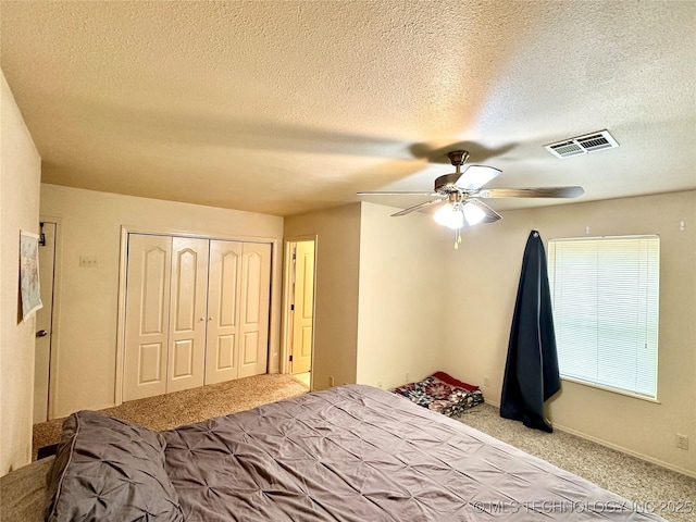 bedroom featuring ceiling fan, light colored carpet, a closet, and a textured ceiling