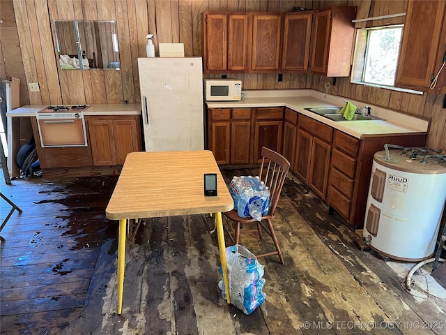 kitchen with dark hardwood / wood-style floors, refrigerator, wood walls, sink, and electric water heater