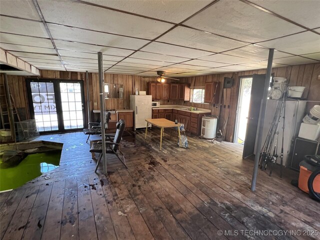 interior space with hardwood / wood-style floors, a drop ceiling, and wooden walls