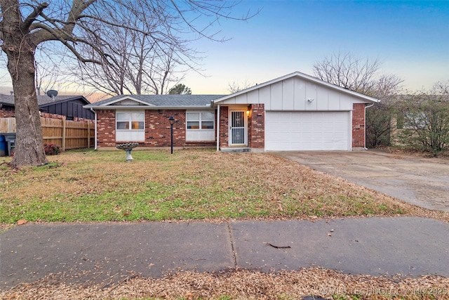 single story home featuring a garage and a lawn