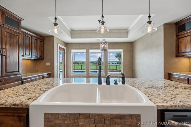 kitchen with crown molding, decorative light fixtures, and a center island with sink