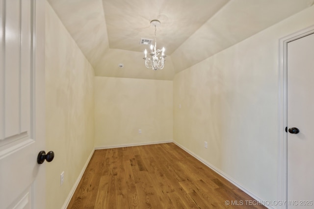 interior space featuring hardwood / wood-style flooring, lofted ceiling, and a notable chandelier