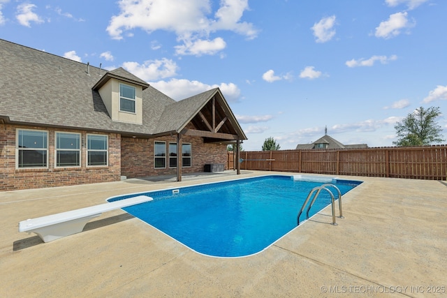 view of swimming pool with cooling unit, a diving board, and a patio