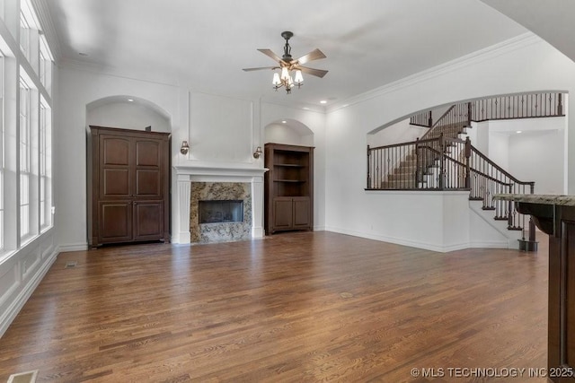 unfurnished living room featuring hardwood / wood-style flooring, a premium fireplace, ornamental molding, and ceiling fan