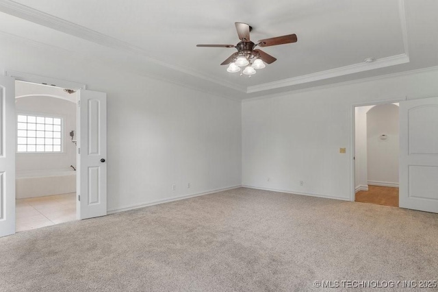 carpeted empty room with ceiling fan, ornamental molding, and a raised ceiling