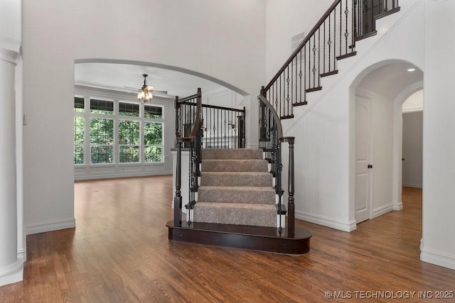 stairs featuring ceiling fan, hardwood / wood-style floors, and a high ceiling