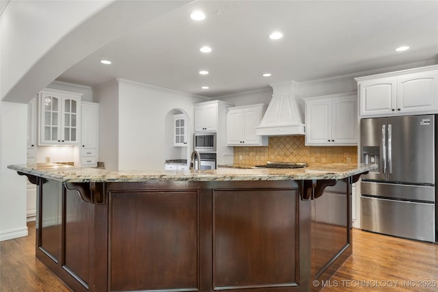 kitchen featuring white cabinetry, stainless steel appliances, light stone countertops, and custom range hood