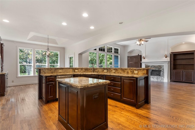 kitchen featuring pendant lighting, ornamental molding, a center island, and dark brown cabinetry