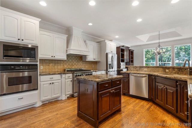 kitchen with appliances with stainless steel finishes, decorative light fixtures, sink, custom exhaust hood, and ornamental molding