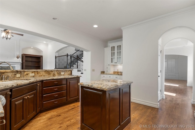 kitchen with sink, a center island, dark brown cabinetry, wood-type flooring, and white cabinets