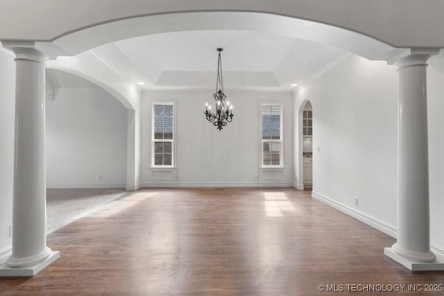 interior space featuring a raised ceiling, decorative columns, and hardwood / wood-style floors