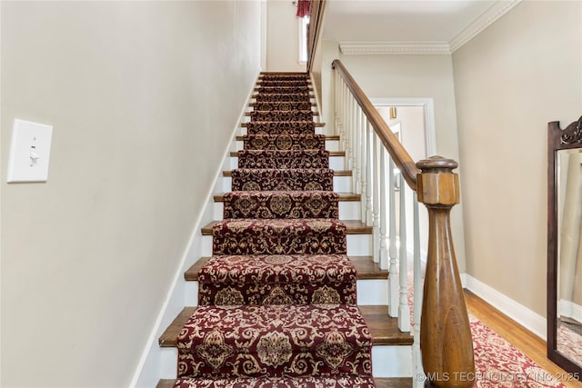 stairway with crown molding and wood-type flooring