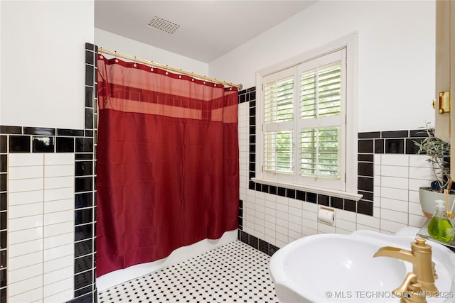 bathroom with tile walls, sink, and curtained shower