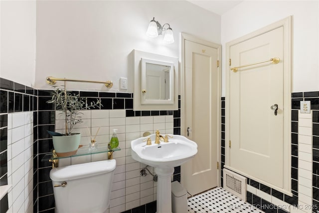 bathroom with toilet, sink, and tile walls