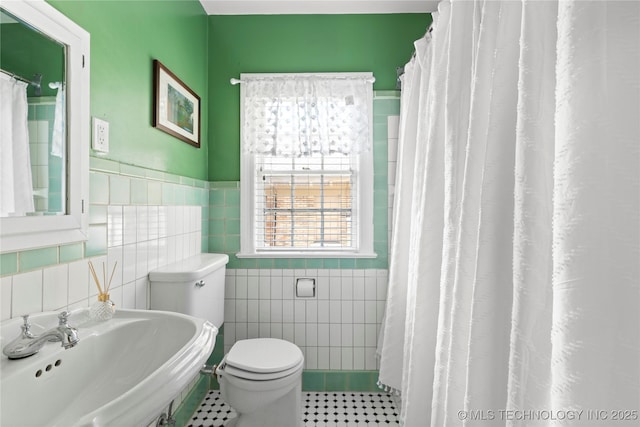 bathroom featuring toilet, tile patterned flooring, sink, and tile walls