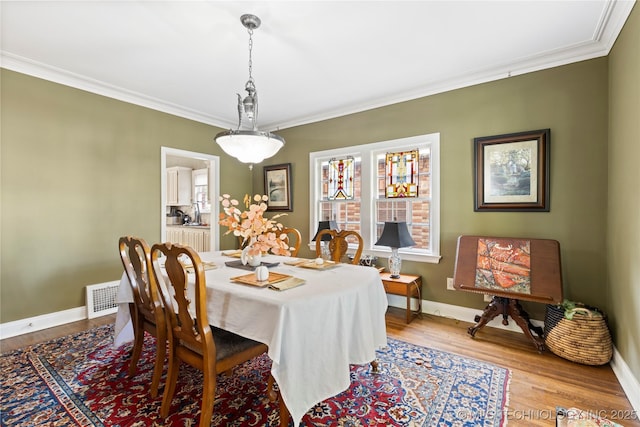 dining room with hardwood / wood-style flooring and ornamental molding