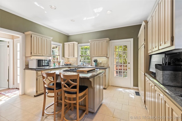 kitchen with light tile patterned flooring, a kitchen island, a breakfast bar, backsplash, and crown molding