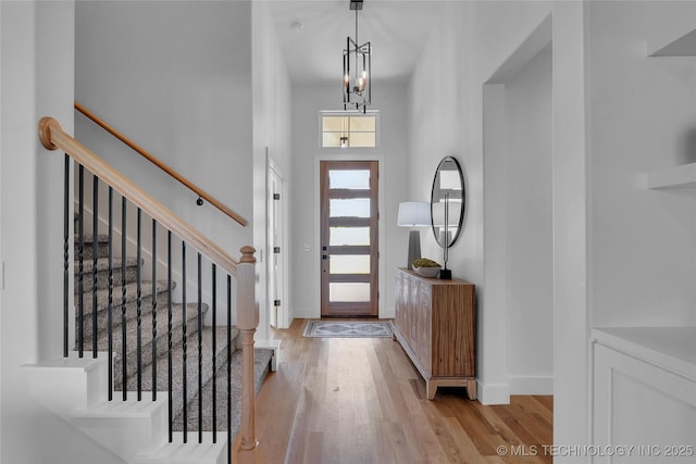 foyer with a towering ceiling, a notable chandelier, and light hardwood / wood-style flooring