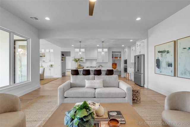 living room featuring ceiling fan and light hardwood / wood-style floors