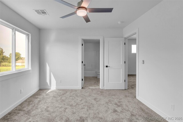 unfurnished bedroom with connected bathroom, light colored carpet, and ceiling fan