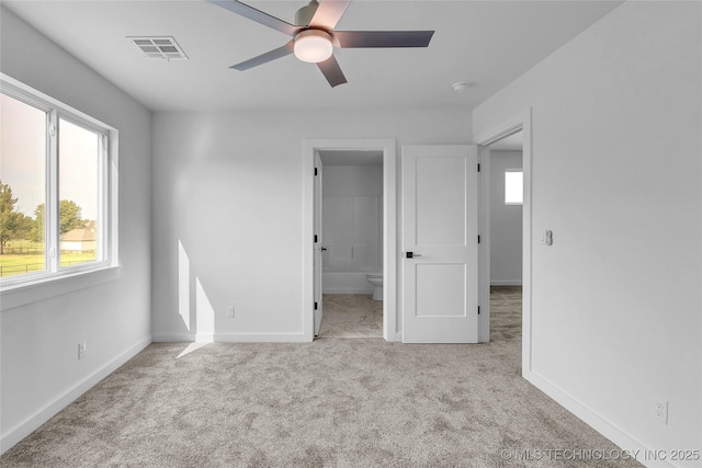 unfurnished bedroom featuring light carpet, connected bathroom, and ceiling fan