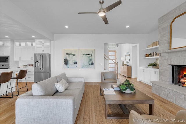 living room featuring ceiling fan, a fireplace, and light hardwood / wood-style flooring