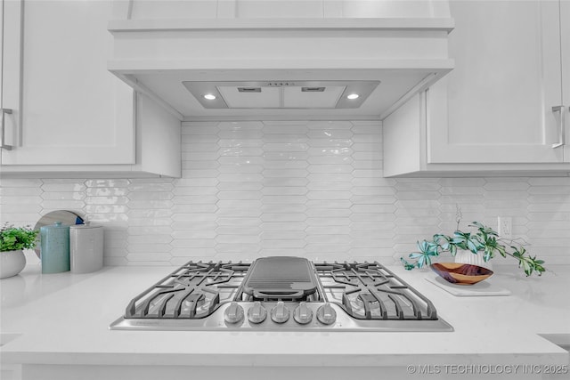 kitchen featuring white cabinetry, tasteful backsplash, stainless steel gas cooktop, log walls, and custom exhaust hood